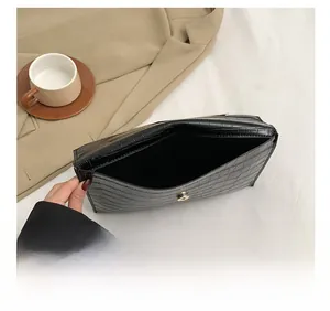 Detail view of the black crocodile pattern clutch interior with a gold magnetic clasp