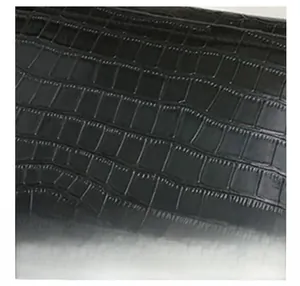 Detailed macro view of black crocodile pattern faux leather texture on fashionable small bag