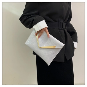 Close-up of white crocodile pattern envelope clutch with gold V-shaped buckle detail