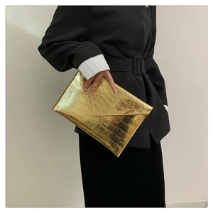 Detail of golden crocodile pattern envelope clutch with V-shaped metal trim decoration
