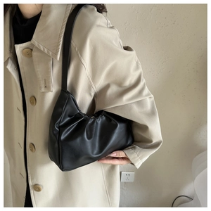 Elegant black pleated cloud shoulder bag shown on model with stylish khaki trench coat