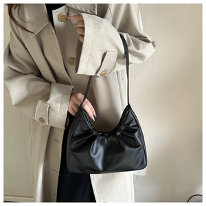 Detail of minimalist black pleated cloud underarm bag with soft faux leather texture