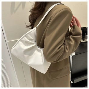 Detailed view of white minimalist pleated cloud underarm bag styled with a brown blazer
