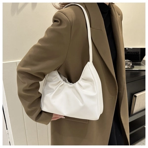 Side view of a white pleated shoulder bag worn by a model in an office setting