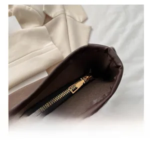 Detail view of smooth golden zipper on dark brown leather tote bag with premium metal teeth