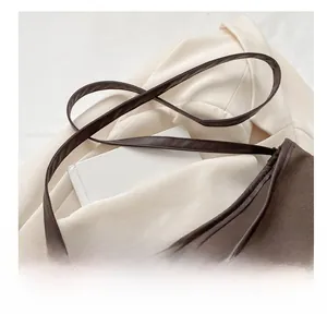 Detail of dark brown shoulder bag with leather strap and metal buckle on beige suit