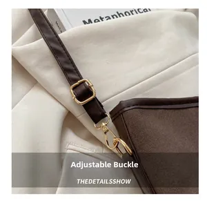 Close-up of adjustable golden buckle and premium dark brown suede texture on a tote bag