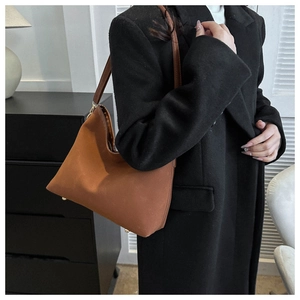 Detail of brown suede tote bag featuring sleek trapezoid design and golden metal rivets