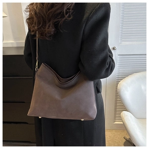 Detail of dark brown matte leather tote bag with gold buckles on female model
