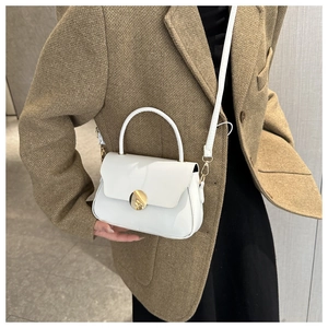 Detail of white leather box bag with gold metal buckle worn with a brown blazer