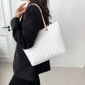 Borsa tote trapuntata bianca con catena dorata indossata da modella in blazer nero