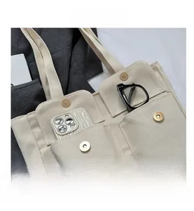 Detail of beige canvas tote bag showing multiple pockets with metal magnetic closures