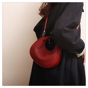 Detail of red woven leather hobo bag worn by a model over a black winter coat