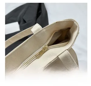 Close-up of a smooth light gold metal zipper closure on an off-white canvas tote bag