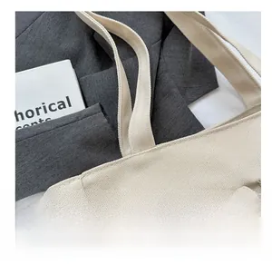 Detail of reinforced shoulder strap stitching and canvas texture on off-white tote bag