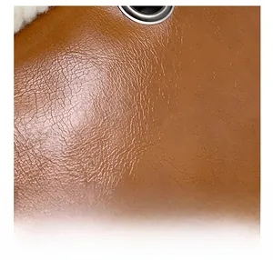 Gros plan sur cuir PU marron avec œillet argenté et détail de doublure en laine blanche