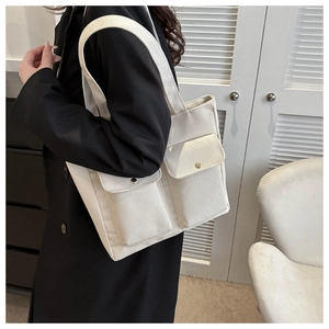 Detail view of off-white canvas tote bag featuring double front pockets with metal buckles