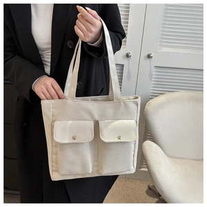 Detail of canvas tote bag showing two front flap pockets with metal magnetic buckles
