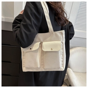 Detailed macro view of cream canvas tote bag showing double front flap pockets with metal buttons