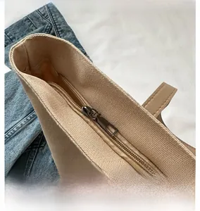 Detail view of smooth metal zipper closure on beige canvas tote bag with high quality texture
