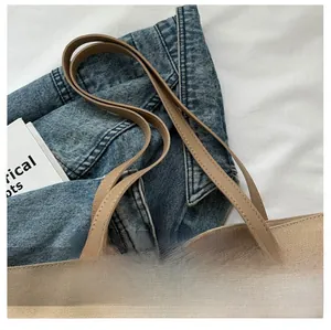 Close-up of khaki canvas tote bag with brown handles on blue denim jacket fabric