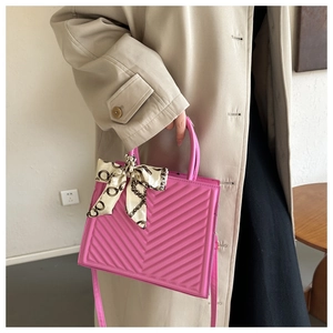 Detail of pink quilted shoulder bag with chain-print silk scarf handle wrap on a model