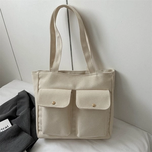 Large off-white canvas tote bag with front utility pockets and adjustable shoulder strap