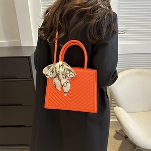Orange quilted tote bag with silk scarf accent shown in a stylish streetwear scene
