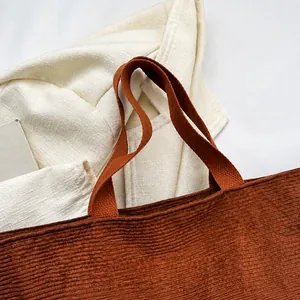 Primer plano de bolso tote de pana marrón oscuro con asas gruesas y textura de canalé