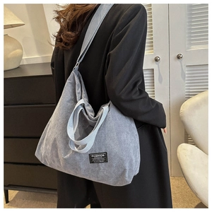 Detail view of light grey corduroy tote bag featuring long strap and woven label texture