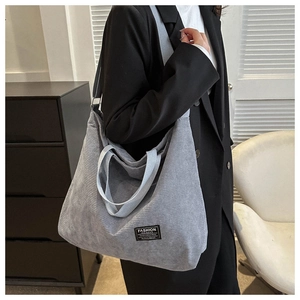 Close-up of grey corduroy tote bag showing large capacity and textured fabric on model