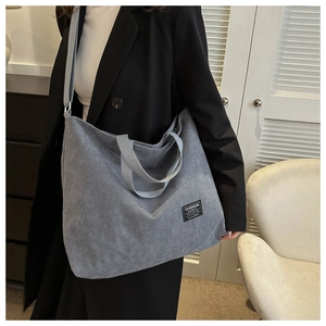 Detailed texture of gray corduroy tote bag showing fashion label and large capacity