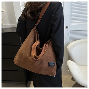 Detail of brown corduroy tote bag showing textured fabric and fashion label on shoulder strap