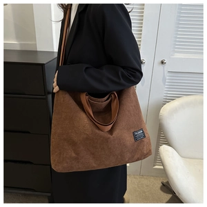 Detail of coffee brown corduroy tote bag showing vertical ribbed texture and fashion label