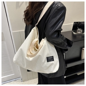 Detailed texture of white corduroy tote bag featuring fashion instinct woven label and strap