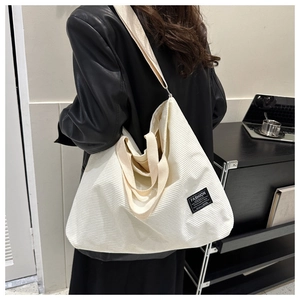 Detail of off-white corduroy tote bag featuring a black fashion instinct textile label