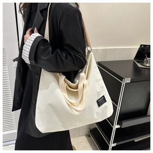 Detail of cream corduroy tote bag showing the texture and black FASHION logo label
