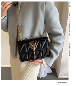 Close-up of black quilted leather crossbody bag with gold chain and tassel detail