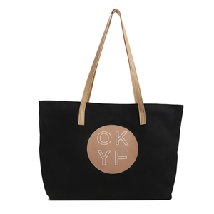 Minimalist black canvas tote bag with brown leather handles and circular OKYF logo detail