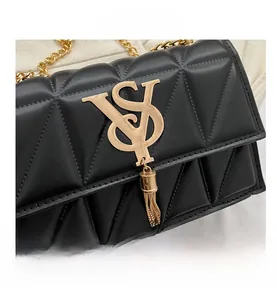 Close-up of black quilted leather shoulder bag with gold chain and metal logo detail