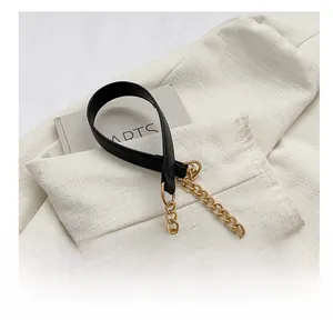 Detail of trendy crossbody bag strap featuring black leather and golden chain links
