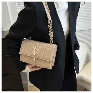 Close-up of quilted beige crossbody bag featuring gold chain strap and chic tassel detail