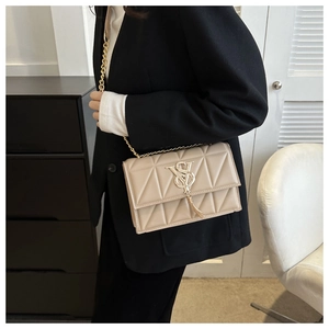 Detailed macro shot of beige quilted leather handbag featuring a gold chain and tassel pendant
