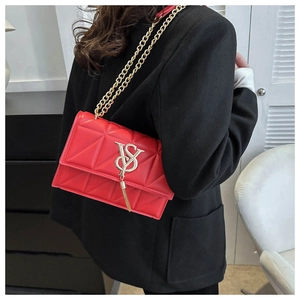 Close-up of red quilted leather handbag with gold chain strap and decorative tassel