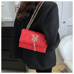 Detail of red quilted crossbody bag with gold VS logo, tassel and chunky chain strap