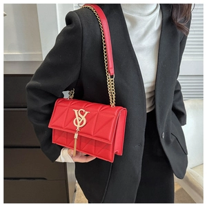 Detail showing red quilted leather texture with gold metal V logo and tassel on handbag