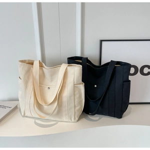 Détail de grands sacs fourre-tout en toile noir et beige avec poches avant à bouton-pression