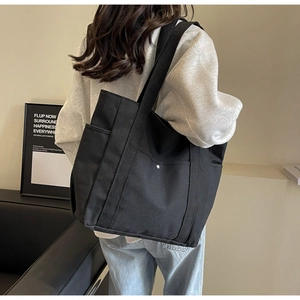 Vue détaillée du grand sac cabas en toile noire avec bouton pression et bandoulière large
