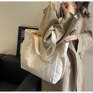 Détail du cabas en toile beige montrant la bandoulière large et la poche latérale pratique
