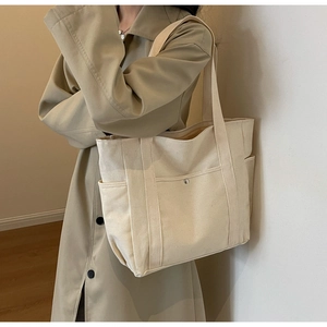 Détail du sac cabas en toile crème avec plusieurs poches et bouton pression métallique